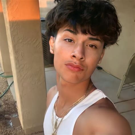 a young man wearing a white tank top posing for the camera