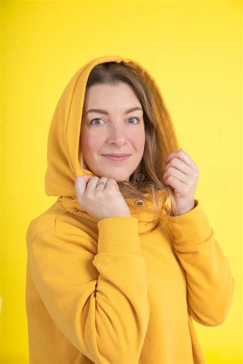 Portrait of Attractive 40-year-old Woman in Yellow Hoodie with Hood on Her Head on Yellow ...