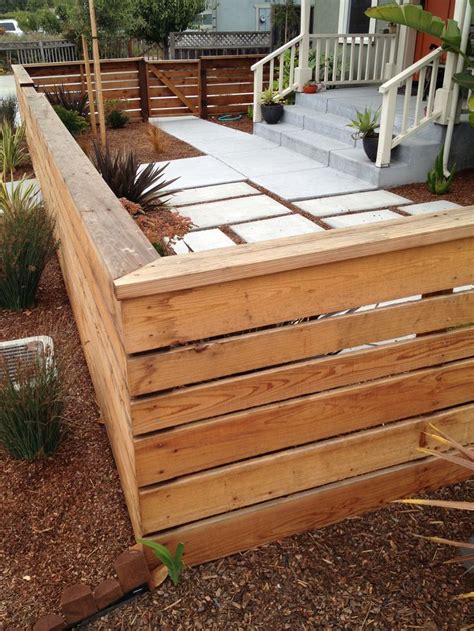 a large wooden fence in front of a house with steps leading up to the porch