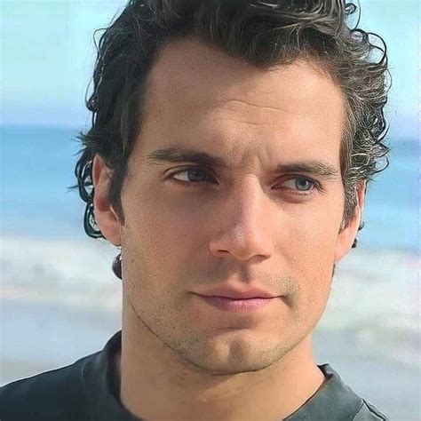 a close up of a person wearing a black shirt near the ocean and sand ...