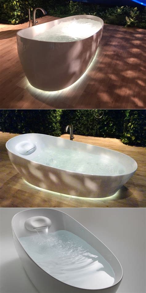 an oval bathtub is lit up in the night and on the ground with water ...