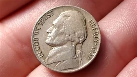 a close up of a person's hand holding a silver lincoln coin in their ...