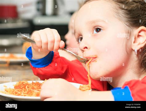 Little girl eat pasta in the kitchen table Stock Photo - Alamy