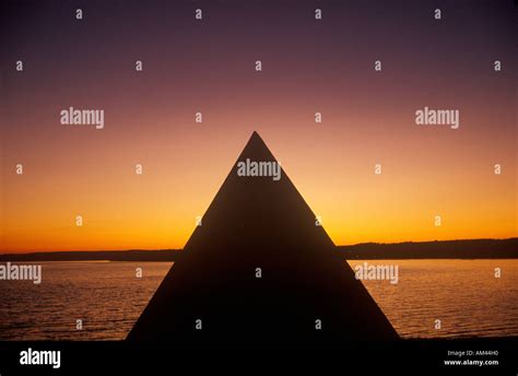 Silhouette of a pyramid by a lake and deepening orange sunset sky Stock Photo - Alamy