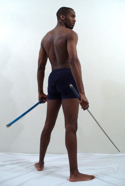 a man with no shirt is holding a stick and wearing blue trunks while standing on a white sheet