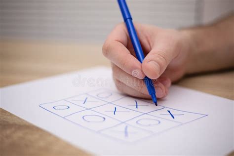 Male Adult Hand Holding Blue Pen Above a Paper with a Tic-tac-toe Game Stock Image - Image of ...