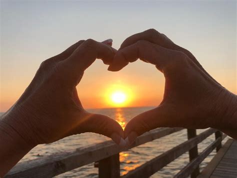 Premium Photo | Cropped hands making heart shape against sun during sunset