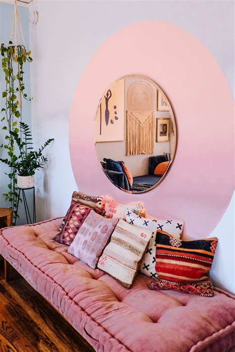a living room with a pink couch and round mirror on the wall