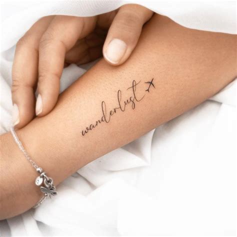 "Wanderlust" lettering tattoo on the forearm.