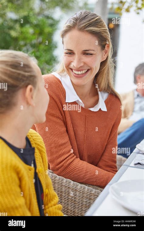Smiling mother and daughter talking at patio table Stock Photo - Alamy