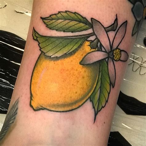 a yellow lemon with leaves and flowers on the side of her leg, next to a flower