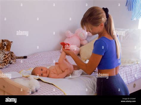 Mother changing babies diaper at home on bed Stock Photo - Alamy