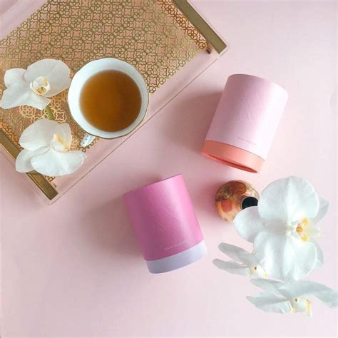 pink and white cups sitting on top of a table next to a cup of tea
