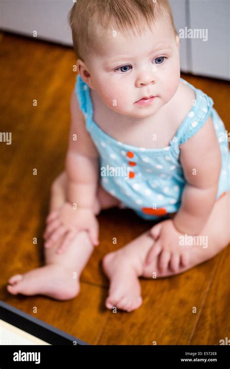 Cute baby girl playing with tablet on wood floor Stock Photo - Alamy
