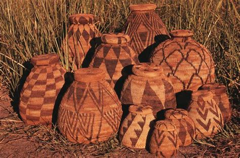 a group of brown vases sitting on top of a dirt ground next to tall grass