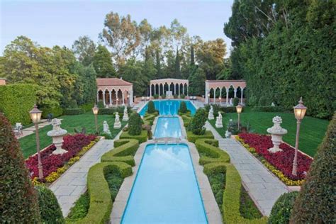 an elaborate garden with a pool surrounded by hedges