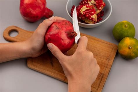 Free Photo | Top view of female hands cutting pomegranates on a wooden ...