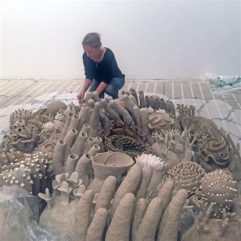 a woman kneeling down on top of a large piece of art made out of clay