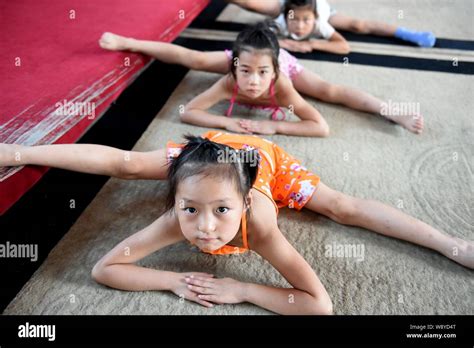 Young Chinese girls bend their bodies and do the splits on the floor to practice gymnastics at a ...