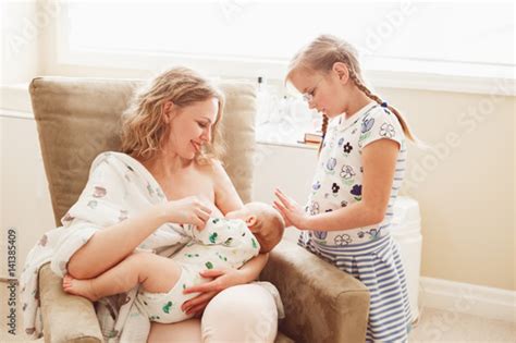 Group portrait of white Caucasian family of three, mother breastfeeding ...