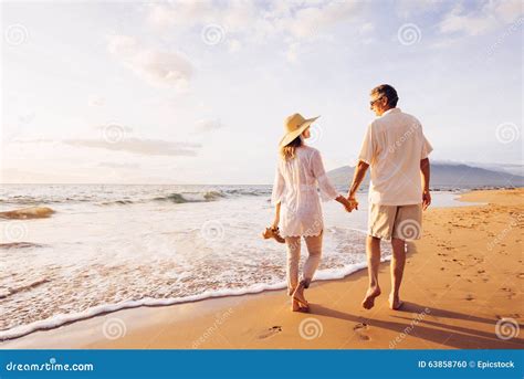 Mature Couple Walking on the Beach at Sunset Stock Photo - Image of ...