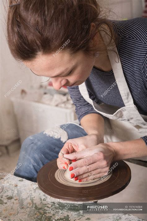 Caucasian woman is shaping pottery clay on a pottery wheel in a ceramic workshop. — creative ...