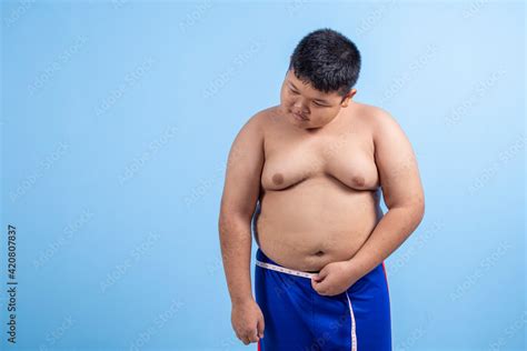 Fat boy with sad face measuring his waist on sky blue background in ...