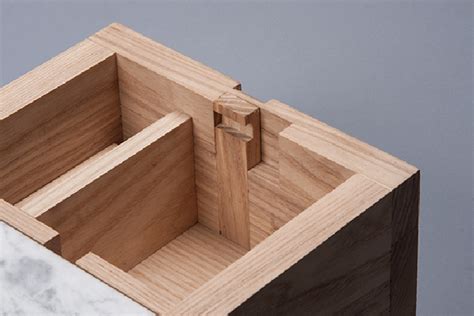 a wooden box with two compartments on the top and one in the middle, sitting on a marble countertop