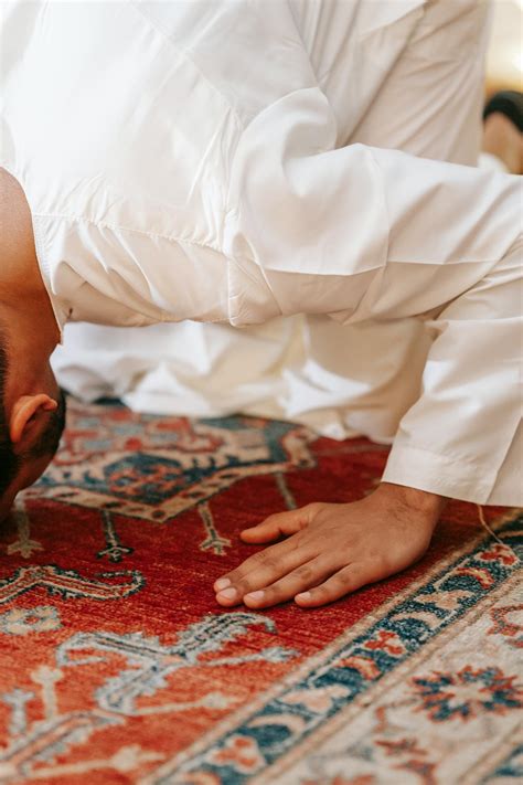 Man in White Thobe Bowing Down on Red and Blue Rug · Free Stock Photo