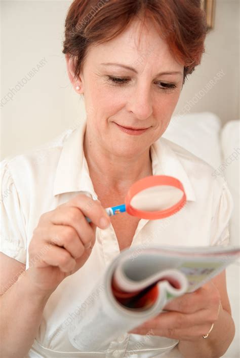 Woman reading with magnifying glass - Stock Image - F005/4131 - Science Photo Library