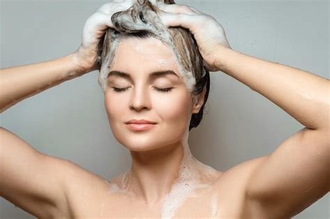 Young beautiful woman is washing her hair with a shampoo - Stock Image ...