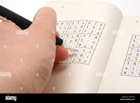 Su doku or Sudoku game on a book with a hand and a pen Stock Photo - Alamy