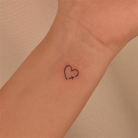 Minimalist cross and heart tattoo on the wrist