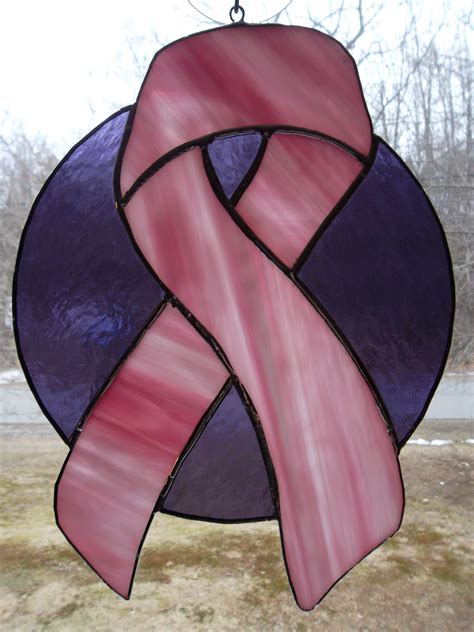 a stained glass window with a pink ribbon hanging from it's center and side