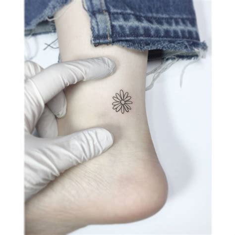 Tiny daisy tattoo on the ankle.