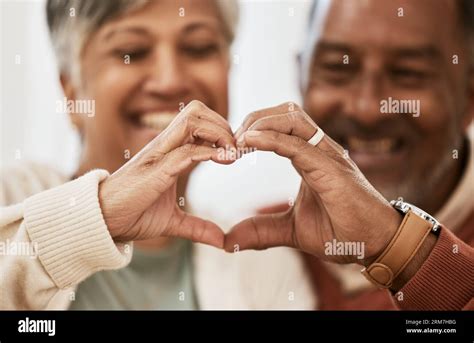 Heart, hands and happy senior couple with love, thank you sign or healthy gesture in their home ...