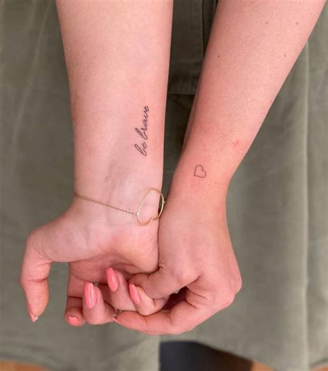 "Be brave" and minimalist heart tattoos on the wrist.