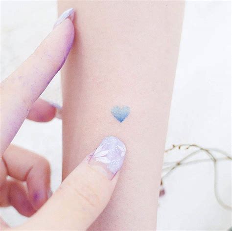 Small blue heart tattoo on the forearm.