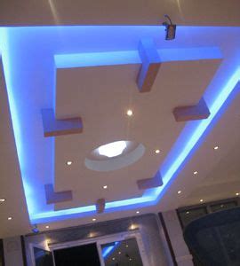 a living room with white walls and blue lighting on the ceiling is lit by recessed lights