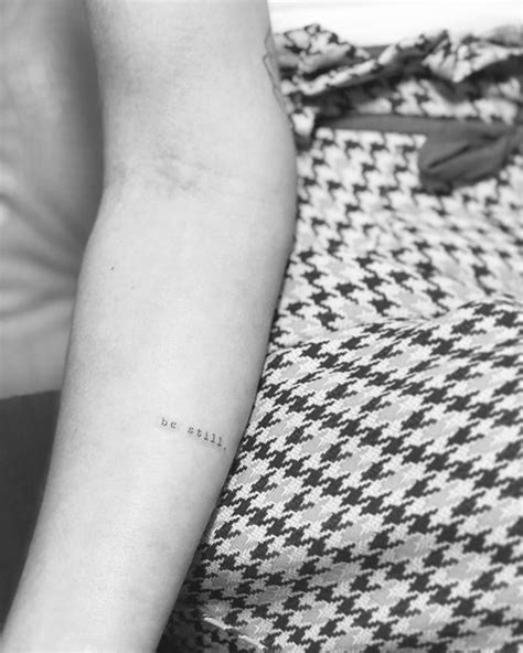 "Be still" tattoo in typewriter font.