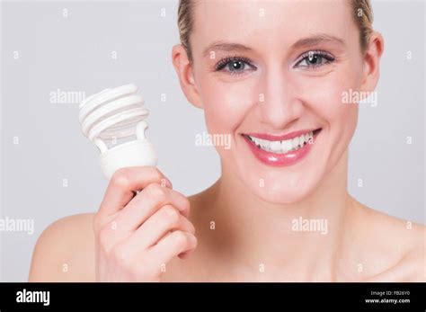 Happy young woman holding energy saving light bulb Stock Photo - Alamy
