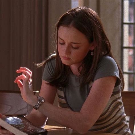 a woman sitting at a table with an electronic device in her hand and looking down