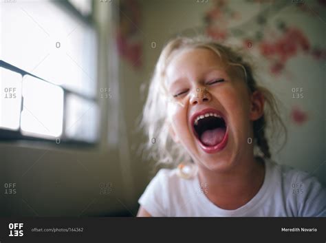 Young girl laughing with mouth open stock photo - OFFSET