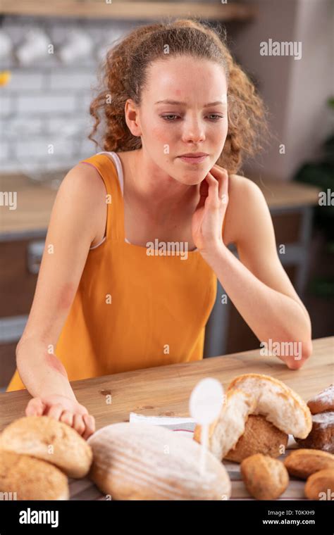 Unpleasant good-looking young lady leaning on kitchen table and rubbing her neck Stock Photo - Alamy