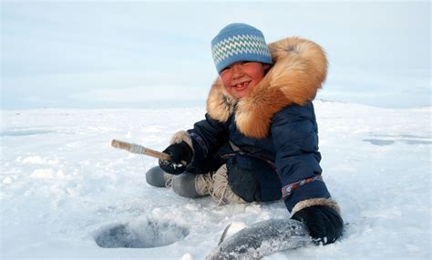 Inuit boy fishing in a hole on a lake in Nunavik, Quebec Province ...