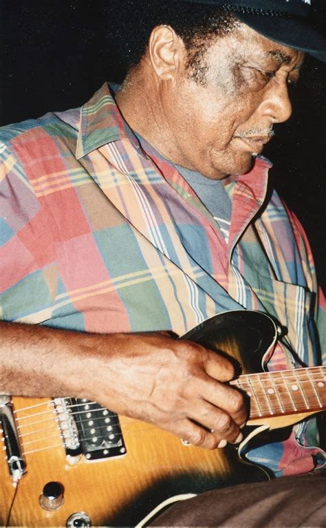 a man playing an electric guitar while wearing a hat