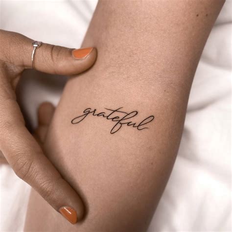 Tattoo of the word "grateful" located on the inner