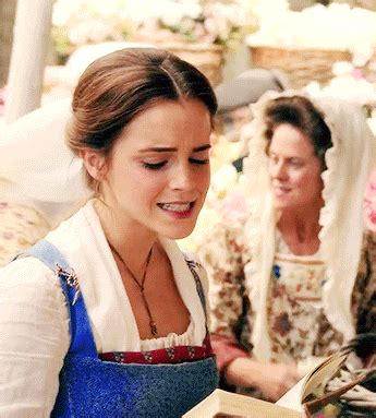 two women dressed in period clothing are looking at an open book