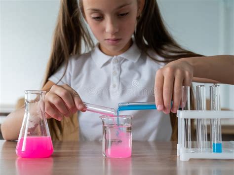 A Schoolgirl Conducts Experiments in a Chemistry Lesson. Girl Pouring Colored Liquids from a ...