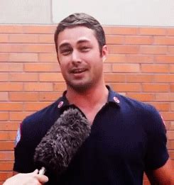 a man holding a microphone in front of a brick wall